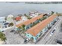 A sunny aerial view shows the turquoise apartment complex near a large bay and ample parking space at 117 7Th N St # 5, Bradenton Beach, FL 34217