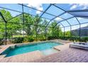 Stunning screened-in pool area featuring a spa, brick patio, and lush landscaping for ultimate relaxation at 13902 Messina Loop, Bradenton, FL 34211
