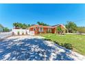 Cozy orange home boasts a well-maintained lawn, complemented by stone and brick pavers at 3053 Monica Pkwy, Sarasota, FL 34234