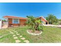 Inviting orange house has a manicured lawn with decorative stone accents surrounding a small palm tree at 3053 Monica Pkwy, Sarasota, FL 34234