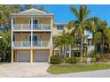 Charming yellow two-story home featuring double balconies, two-car garage, and lush tropical landscaping at 306 Poinsettia Rd, Anna Maria, FL 34216