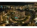 Nighttime aerial view of the condo building with illuminated pool and surrounding city lights at 325 Golden Gate Pt # 1004, Sarasota, FL 34236