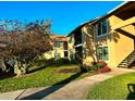 Condominium exterior showcasing lush landscaping, manicured lawn, and covered staircase under a clear sky at 4005 Crockers Lake Blvd # 11, Sarasota, FL 34238