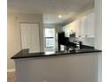Bright kitchen with white cabinetry, black appliances and countertops, and hardwood floors at 4005 Crockers Lake Blvd # 11, Sarasota, FL 34238