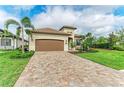 Beautiful home showcasing a two-car garage, paver driveway, manicured lawn, and vibrant tropical landscaping at 5810 Brandon Run, Bradenton, FL 34211