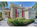 Charming home exterior with stone accents, red shutters, landscaped garden and well-manicured lawn at 6642 Oakland Hills Dr, Lakewood Ranch, FL 34202