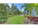 Beautifully landscaped backyard with green grass, tropical plants, and a serene patio area at 8110 Trimbelle Ter, Parrish, FL 34219