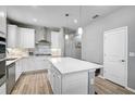 Bright kitchen with white cabinets, stainless steel appliances, an island, and stylish pendant lighting at 8313 Ocean Tides Cv, Parrish, FL 34219