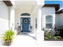 Inviting front porch features a blue door with wreath, complemented by elegant columns and vibrant plants at 13130 50Th E Ct, Parrish, FL 34219