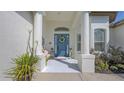 A charming front porch features a blue door, a bench, and elegant columns, creating a welcoming entrance at 13130 50Th E Ct, Parrish, FL 34219