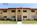 Exterior view of the condo featuring yellow walls, a red tile roof, and a well-manicured lawn at 1431 57Th W St # 1431, Bradenton, FL 34209