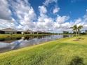 Picturesque view of the lake, showcasing the lush green lawn, serene water, and clear blue sky with fluffy clouds at 208 Potenza Loop, Nokomis, FL 34275