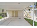 Covered carport featuring two storage units, staircase access to upper unit, and concrete flooring at 208 Silver Lake Dr # 101, Venice, FL 34292