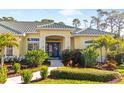 Inviting home featuring a blue double-door entry, lush tropical landscaping, and a well-manicured lawn at 2196 Muskogee Trl, Nokomis, FL 34275