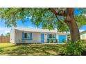Quaint one-story home showcasing charming blue accents, a manicured lawn, and a mature shade tree at 2237 Lockwood Meadows Cir, Sarasota, FL 34234