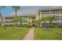 Multi-story condo building with manicured lawn and mature palm trees in a tropical setting at 225 Hourglass Way # 306, Sarasota, FL 34242