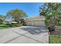 Spacious driveway leading to an attached two-car garage; the yard has mature trees and landscaping at 5032 Timber Chase Way, Sarasota, FL 34238