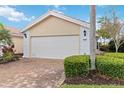 An exterior shot of a two car garage featuring a brick driveway and well maintained landscaping at 6209 Erice St, Venice, FL 34293