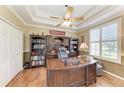 Elegant office with a wooden desk, built-in bookcases, plantation shutters, and a tray ceiling at 8136 Snowy Egret Pl, Bradenton, FL 34202