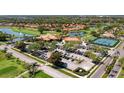 Aerial view of a golf community featuring a clubhouse, tennis courts, and scenic ponds at 4812 Sand Trap E Cir, Bradenton, FL 34203