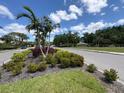 Community entrance featuring lush landscaping, flowering plants, and palm trees at 4812 Sand Trap E Cir, Bradenton, FL 34203
