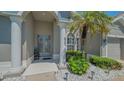 Inviting front entrance with pillars, a decorative door, and lush landscaping with palm tree at 1085 Mallard Marsh Dr, Osprey, FL 34229