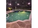 A screened in pool and hot tub with stone patio are illuminated at dusk at 14239 Nighthawk Ter, Lakewood Ranch, FL 34202