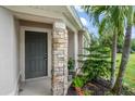 Close-up of front door featuring stone pillar, green plants, and lush tropical landscaping at 15032 Skip Jack Loop, Lakewood Ranch, FL 34202