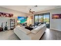 Bright living room with large sectional sofa, ceiling fan, and sliding glass doors to the lanai at 15719 Barefoot Beach Dr, Lakewood Ranch, FL 34211
