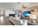 Open living room features a large television, modern ceiling fan, and adjacent dining area for easy entertaining at 15719 Barefoot Beach Dr, Lakewood Ranch, FL 34211