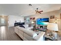 Bright living room with a white leather sofa, ceiling fan, and television with beach image at 15719 Barefoot Beach Dr, Lakewood Ranch, FL 34211