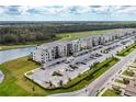 Aerial view of beige condos with covered parking, lake and golf course in the background with landscaping and streets at 18114 Gawthrop Dr # 306, Bradenton, FL 34211
