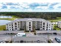 Beige condo building with covered parking with palm trees and parking spaces with a lake and trees in the background at 18114 Gawthrop Dr # 306, Bradenton, FL 34211