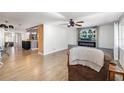 Open-concept living room with wood floors, a ceiling fan, a large flat screen television, and a fire place at 2929 Siesta Dr, Venice, FL 34293