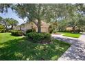 Home exterior with a clay tile roof, a well-manicured lawn, mature trees, and beautiful landscaping at 4713 Sweetmeadow Cir, Sarasota, FL 34238