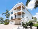 Bright, multi-story home showcasing spacious balconies, covered parking, and a charming coastal aesthetic amidst lush greenery at 497 Island Cir, Sarasota, FL 34242