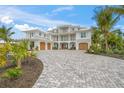 Elegant home featuring a paved driveway, multiple garages, and lush tropical landscaping at 619 Key Royale Dr, Holmes Beach, FL 34217