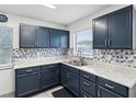 Bright kitchen featuring blue cabinets, stainless steel sink, and decorative backsplash at 13241 Miami St, Hudson, FL 34667