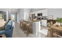 Open-concept kitchen features a granite-topped island with seating and stainless steel appliances; dining area visible at 16198 Arcaro Ave, Port Charlotte, FL 33954