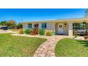 Well-maintained home with a welcoming front porch, brick pathway, and colorful flowerbeds, and lush grass at 2605 Sunnybrook Dr, Sarasota, FL 34239