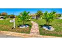 Beautifully landscaped front yard featuring a brick pathway, green lawn, and vibrant palm trees at 2605 Sunnybrook Dr, Sarasota, FL 34239