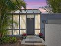 Stylish home entrance with a glass-paneled door, bright curtains, and potted flowers, creating a welcoming ambiance at 2720 Herwald St, Sarasota, FL 34231
