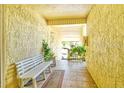Well-lit condo hallway with tile floors, bench, and inviting greenery at 3403 Clark Rd # 203, Sarasota, FL 34231