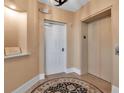 Hallway featuring tan walls, an elevator, and a white entry door at 3621 North Point Rd # 603, Osprey, FL 34229