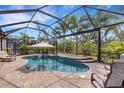 Screened-in pool area with a beautiful in-ground pool, jacuzzi, and lovely brick patio surrounded by green landscaping at 3921 Waypoint Ave, Osprey, FL 34229