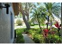 A view from the side of the house featuring the walkway, lush landscaping, trees, and mailbox in the background at 3954 Wilshire Cir # 165, Sarasota, FL 34238