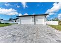 Paver driveway leading to a spacious three-car garage with white doors, set against a manicured lawn at 5322 Syracuse Rd, Venice, FL 34293