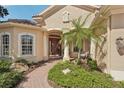 Inviting front porch with brick pathway, lush plants, and comfortable seating area at 5412 Royal Poinciana Way, North Port, FL 34291