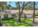 Well-kept home with a tile roof, manicured lawn, and mature trees, offering a tranquil and inviting curb appeal at 5712 Garden Lakes Fern, Bradenton, FL 34203