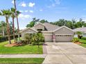 Charming home showcasing a well-manicured lawn, lush landscaping, and a welcoming three-car garage on a beautiful day at 5907 90Th Avenue E Cir, Parrish, FL 34219